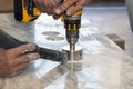 handyman cut round holes for electrical outlets in marble countertop for the kitchen using hand drill Royalty Free Stock Photo