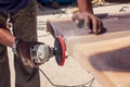 A handyman grinding wooden plank outdoor