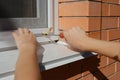 Handyman installing mosquito net, mosquito wire screen on brick house window. Royalty Free Stock Photo