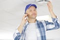 handyman installing smoke detector calling with phone Royalty Free Stock Photo