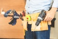 Handyman manual worker in tools belt and holding drill in his hands, Carpenter working with equipment in wood workshop, man doing Royalty Free Stock Photo