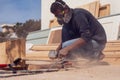 A handyman polishing wooden plank outdoor