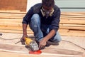 A handyman polishing wooden plank outdoor