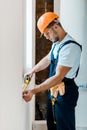 Handyman measuring wall with yellow measuring tape