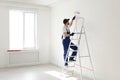 Handyman painting wall with roller brush indoors. Professional construction tools