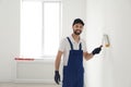 Handyman painting wall with roller brush indoors. Professional construction tools