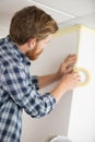 handyman prepares walls for painting with masking tape