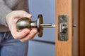 An Carpenter shoves the door handle spindle through the face bore and the latch assembly