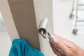 Handyman putting up wallpaper on the white walls