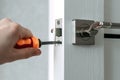 Handyman repair the door lock in the room. The concept repair yourself. Selective focus. Royalty Free Stock Photo