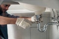 Close up of indian plumber is repairing faucet of a sink at bathroom using adjustable wrench Royalty Free Stock Photo