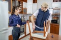 Handyman repairing furniture in the kitchen. He repairs a chair with a screwdriver.