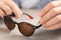 Handyman repairing sunglasses with screwdriver at table, closeup