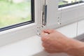Handyman repairs plastic window with a hexagon. Workman adjusts the operation of the plastic window Royalty Free Stock Photo