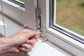 Handyman repairs plastic window with a hexagon. Workman adjusts the operation of the plastic window