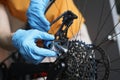 Handyman in rubber gloves fixing brakes of bicycle closeup