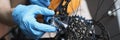 Handyman in rubber gloves fixing brakes of bicycle closeup