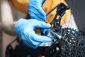Handyman in rubber gloves repairing bicycle in workshop closeup