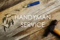 Handyman service written on wooden background with screwdriver and hammer