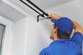 Handyman services - worker installing window curtain rod on the wall