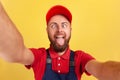 Handyman in uniform taking selfie, looking at camera with crossed eyes and showing tongue out POV. Royalty Free Stock Photo