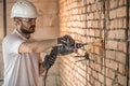 Handyman uses jackhammer, for installation, professional worker on the construction site. The concept of electrician and handyman