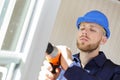 handyman using cordless screwdriver to install window