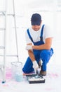 Handyman using paint roller in tray at home