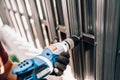 Handyman worker using electrical cord screwdriver for fastening screws into metal fence