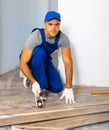 Handyman worker in work clothes use rubber hammers installing laminate panel in apartment