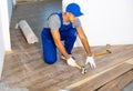 Handyman worker in work clothes use rubber hammers installing laminate panel in apartment