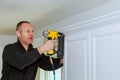 Handyman working instal brad nail gun to Crown Moulding wall cabinets framing trim