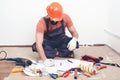 Handyman writing a plan of work. Builder wears safety helmet. Builder tools on a floor. House renovation service