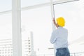 Handyman in yellow hard hat examining window in office