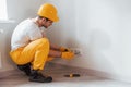 Handyman in yellow uniform works with electricity and installing new socket. House renovation conception