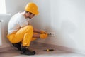 Handyman in yellow uniform works with electricity and installing new socket. House renovation conception