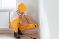 Handyman in yellow uniform works with electricity and installing new socket. House renovation conception