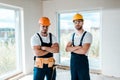 Handymen in helmets and goggles standing with crossed arms