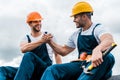 Handymen holding hands while smiling against sky Royalty Free Stock Photo