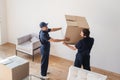 handymen in uniform carrying cardboard box