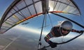 Hang glider pilot on colorful wing flies together with eagle