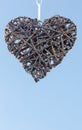 Hanged heart made from woven wooden sticks on blue sky background Royalty Free Stock Photo