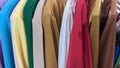 On a hanger in a clothing store hang colorful shirts and jackets on hangers in a row