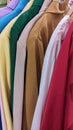 On a hanger in a clothing store hang colorful shirts and jackets on hangers in a row