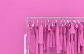 Hanger with pink women`s clothing against the background of a pink wall. Monotonous pink clothes. Creative conceptual illustratio