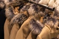 Hangers with autumn`s  and winter women`s  wear in shop. Beige  coats with  furs collars Royalty Free Stock Photo