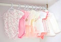 Colorful, cute girl baby dresses hanging on rack in wardrobe. Baby fashion concept design. Royalty Free Stock Photo