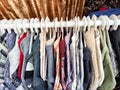 Hangers with a variety of clothes on a white rack. Home storage of clothes. Clutter. Littery. Declutter. Garage sale