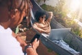 Hanging around online and outside. a young woman using a laptop and relaxing on a hammock while her boyfriend uses a Royalty Free Stock Photo