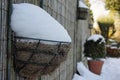 a hanging basket covered in thick snow with defocused garden